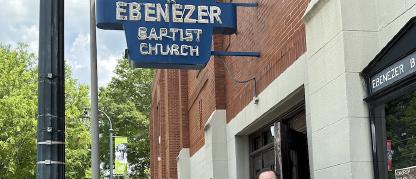 Group of people standing in front of a building under a sign that says Ebenezer Baptist Church.