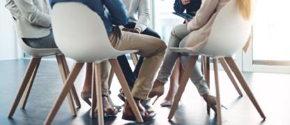 A group of people sitting in chairs having a conversation