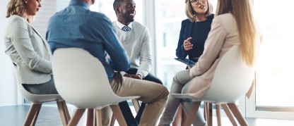 A group of people sitting in chairs having a conversation